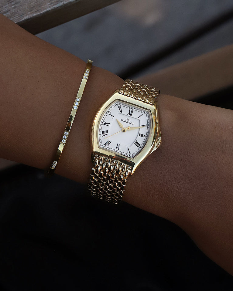 A square womens watch in 22k gold plated 316L stainless steel from Waldor & Co. with domed mineral glass dial. Seiko movement. The model is Constant 36 Menaggio.