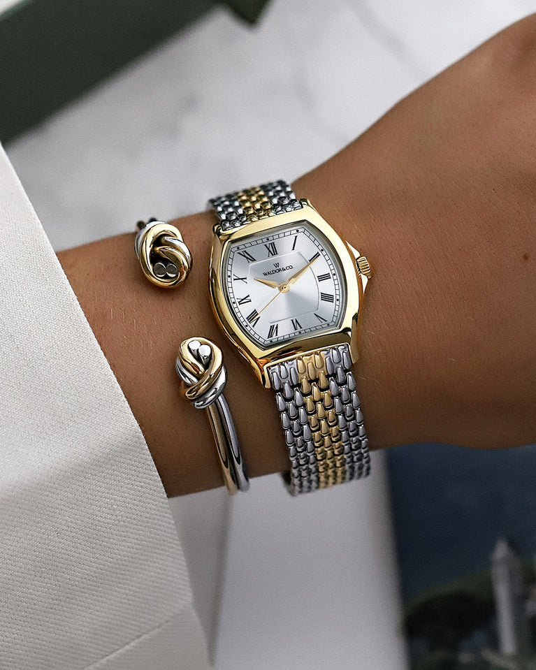 A square womens watch in 22k two-toned silver and gold plated 316L stainless steel from Waldor & Co. with domed mineral glass dial. Seiko movement. The model is Constant 36 Menaggio.