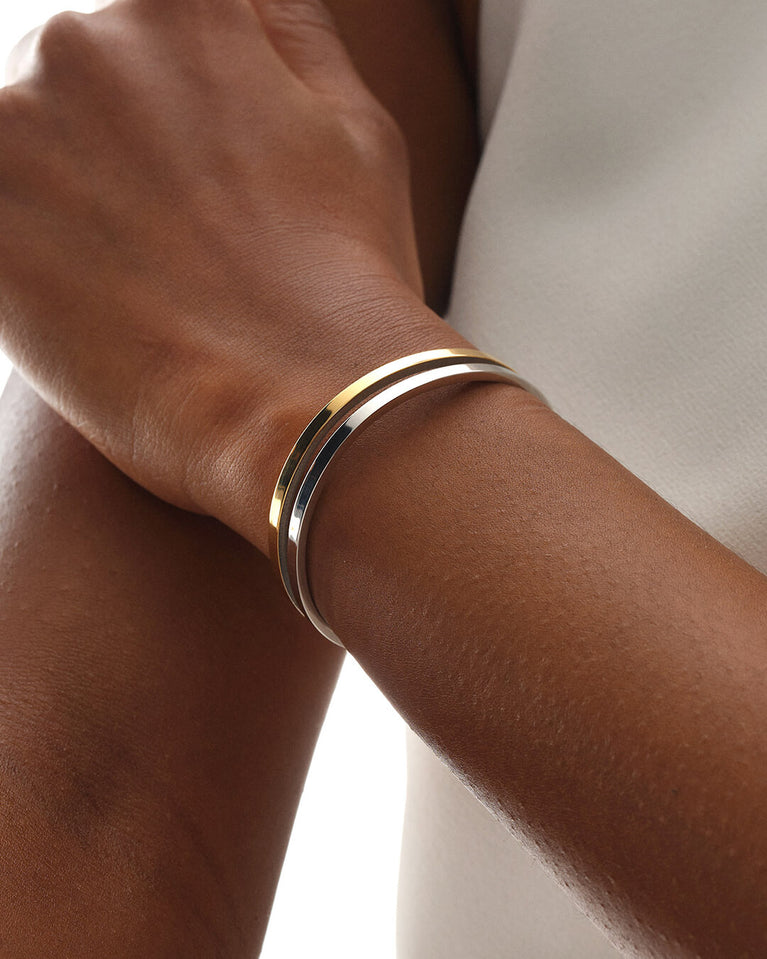 A Bangle in polished silver 316L stainless steel from Waldor & Co. One size. The model is Dual Bangle Polished.