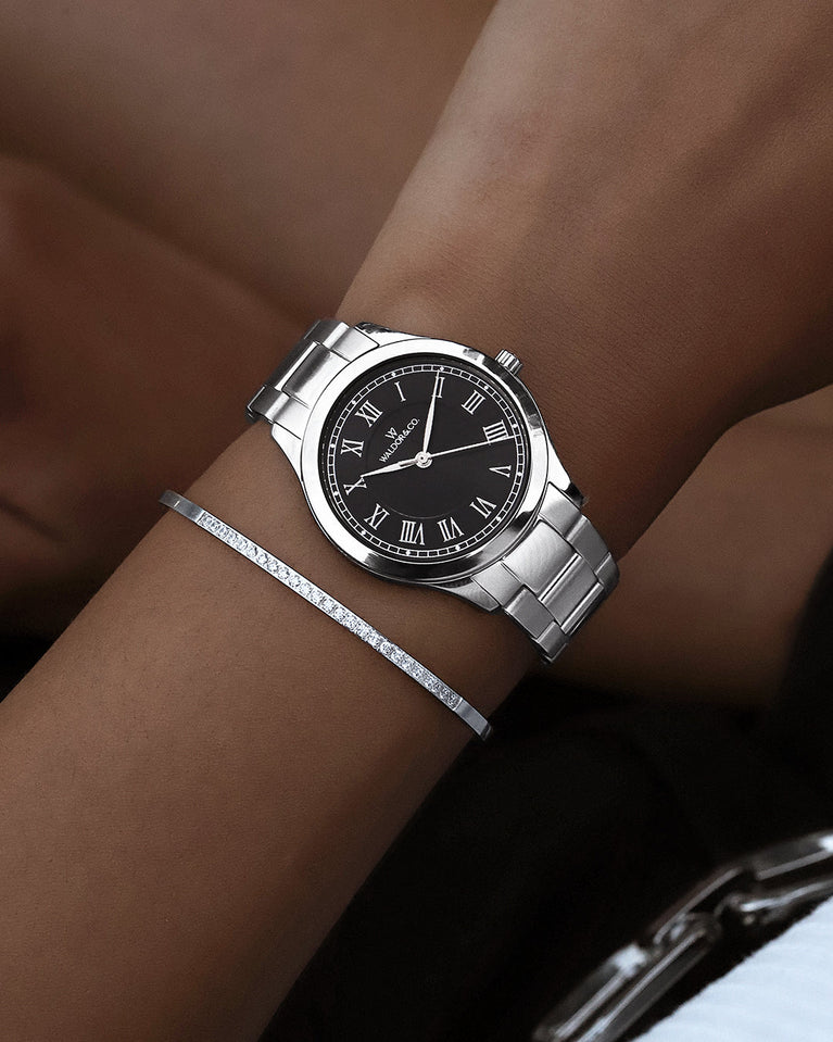A round womens watch in silver from Waldor & Co. with black sunray dial and a second hand. Seiko movement. The model is Imperial 32 Nocelle 32mm.