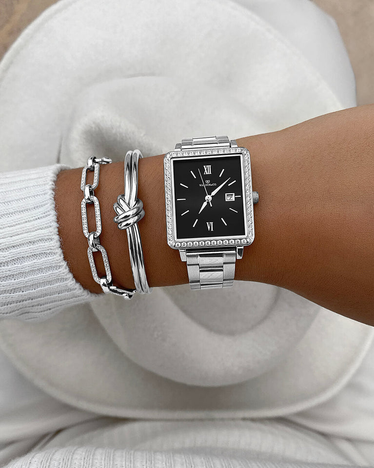  A square womens watch in silver with stones from WALDOR & CO. with black sunray dial and a second hand. Seiko VJ22 movement. The model is Delight 32 Mayfair 28x32mm. 