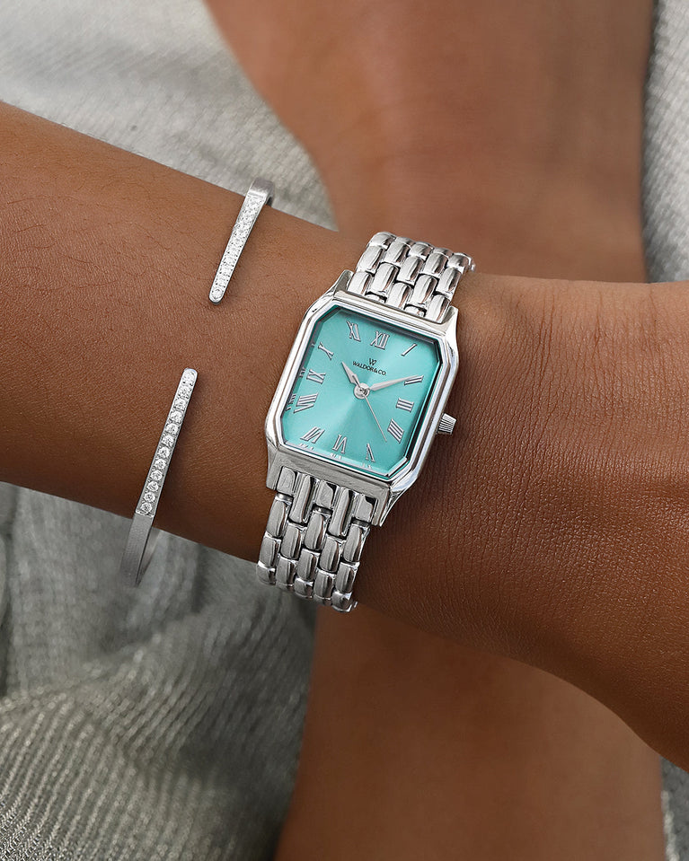 A square womens watch in Rhodium-plated 316L stainless steel from Waldor & Co. with turquoise Diamond Cut Sapphire Crystal glass dial. Seiko movement. The model is Eternal 22 Bellagio.