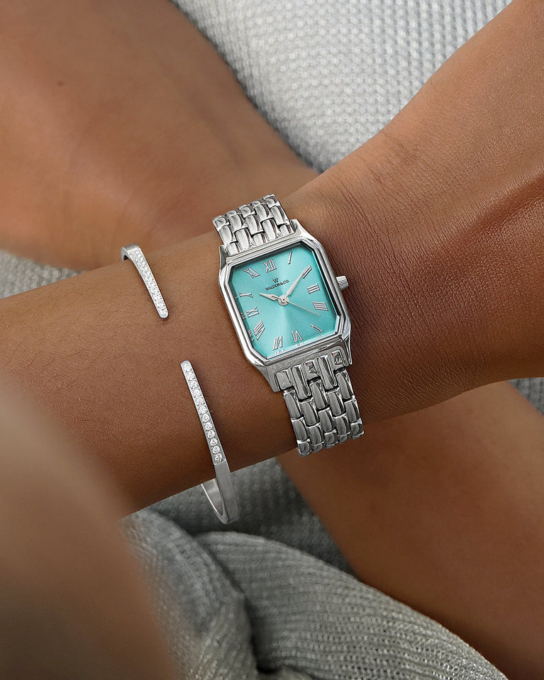 A square womens watch in Rhodium-plated 316L stainless steel from Waldor & Co. with turquoise Diamond Cut Sapphire Crystal glass dial. Seiko movement. The model is Eternal 22 Bellagio.