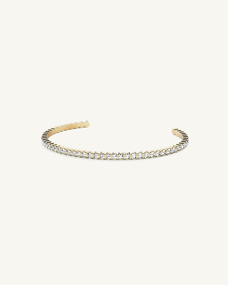 A polished stainless steel bangle in 14k gold from Waldor & Co. One size. The model is Grace Bangle Polished.