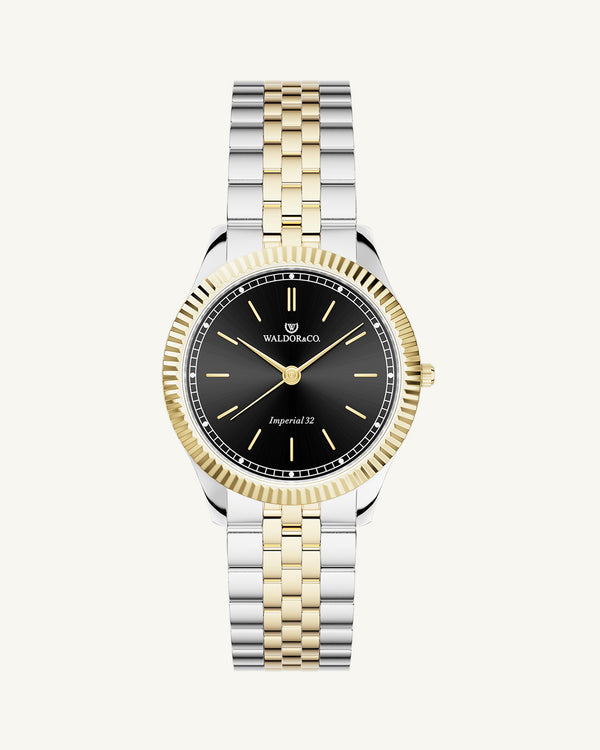 A round womens watch in silver and 14k gold from Waldor & Co. with black sunray dial and a second hand. Seiko movement. The model is Imperial 32 Positano 32mm.
