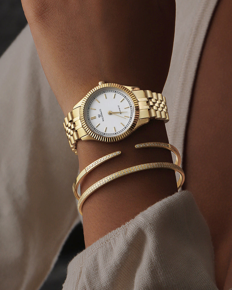 A round womens watch in 14k gold from Waldor & Co. with white sunray dial and a second hand. Seiko movement. The model is Imperial 32 Positano 32mm.
