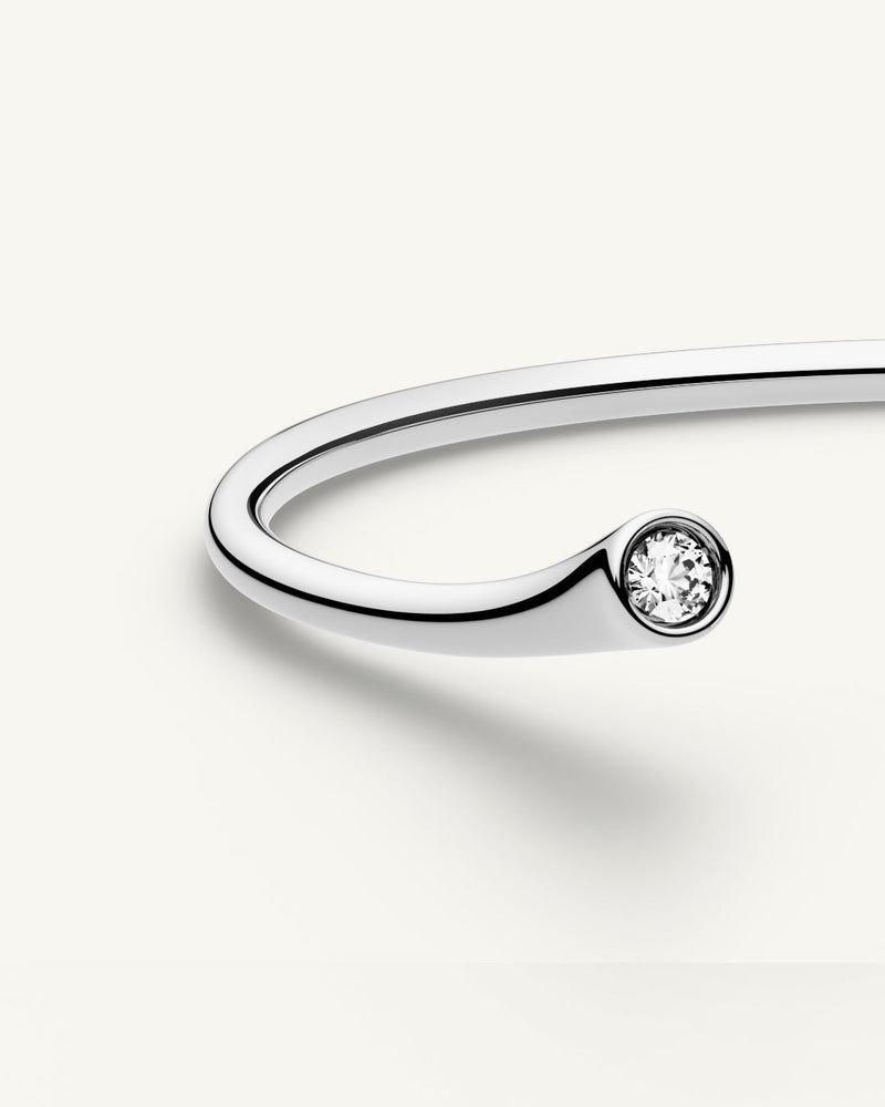 A polished stainless steel bangle from Waldor & Co. One size. The model is Delight Bangle.