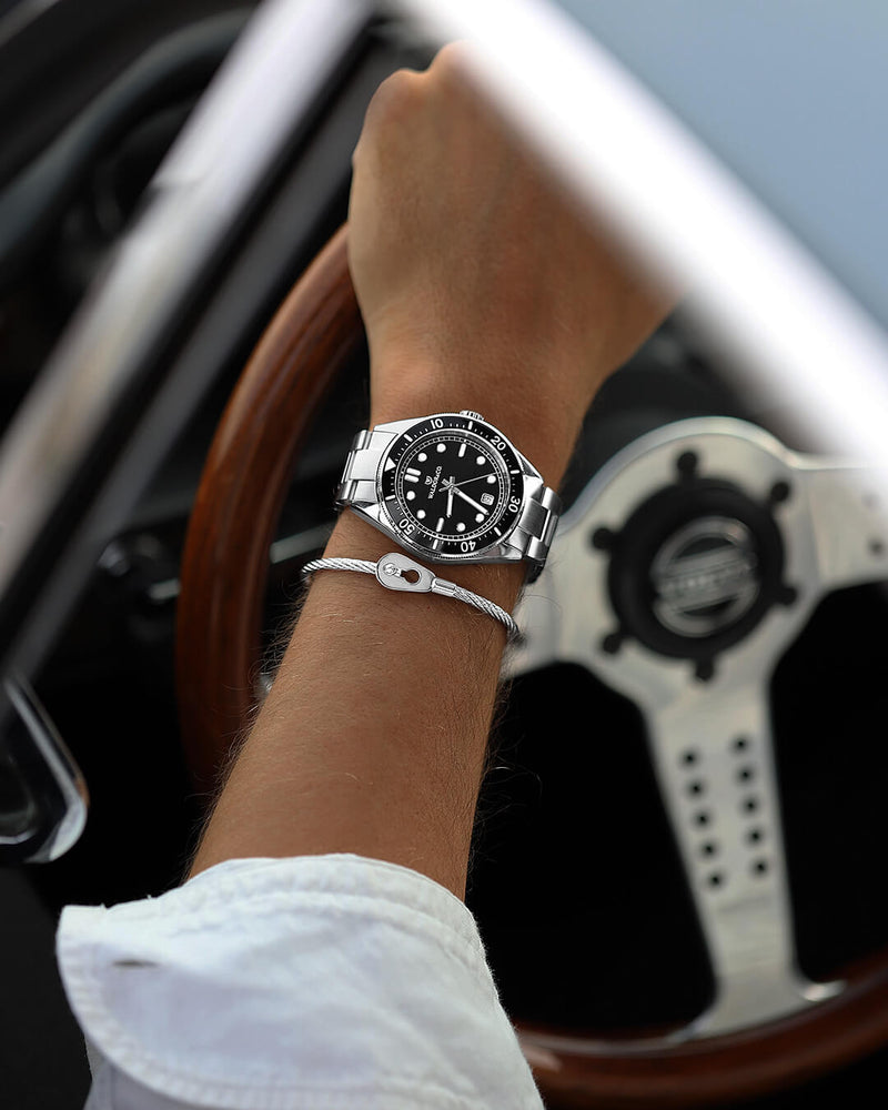 A round mens watch in Rhodium-plated 316L stainless steel from Waldor & Co. with Black dial in brass with a rotating bezel. Applied indices, luminous hands. Ronda 715. The model is Novel 40 Cap d’Ail 40mm.
