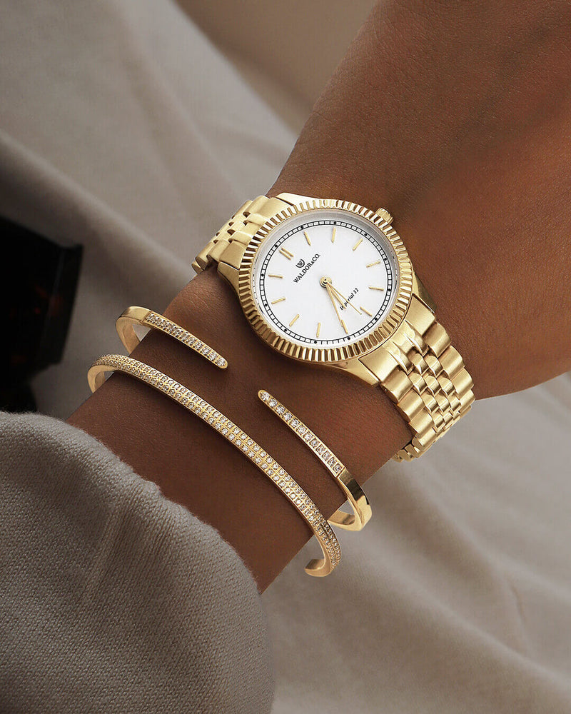 A round womens watch in 14k gold from Waldor & Co. with white sunray dial and a second hand. Seiko movement. The model is Imperial 32 Positano 32mm.